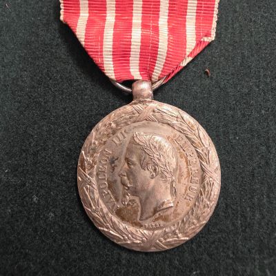 une médaille d'argent entourée d'un ruban rouge et blanc