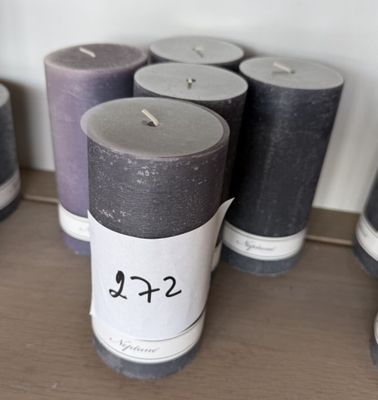 Plusieurs bougies sont alignées sur une étagère, accompagnées d'une étiquette de prix
