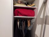 un petit placard sur lequel sont posés beaucoup de vêtements