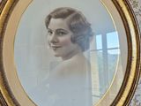 Une vieille photo représentant une femme en robe blanche est accrochée au mur.