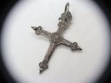 a silver cross on a white surface with a black background
