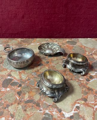 four silver dishes sitting on a table with a red background