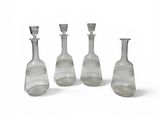 cinq vases en verre posés les uns à côté des autres sur une surface blanche