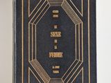 an old black book with gold lettering on it sitting on a white surface
