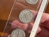 a person holding three silver coins in a clear box