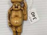 une petite statue représentant un homme tenant un chapeau attaché à une ficelle