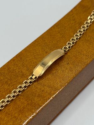 an image of a gold bracelet with a clasp on a wooden box