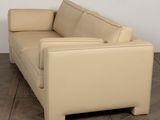 beige leather sofa in a room with wood flooring and a white wall