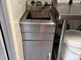 a small kitchen with a sink and a trash can in it