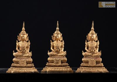 trois statues de Bouddha en or posées sur une surface noire