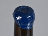 a close up of a bottle of beer with a blue liquid on it