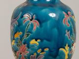 a blue vase with flowers on it sitting on a table
