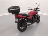 a red motorcycle parked in a room with a helmet on the back of it
