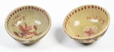 pair of small bowls with floral designs on them on a white surface