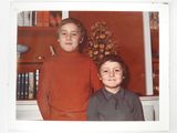 two young boys standing next to each other in front of a book shelf