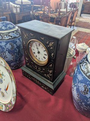 a clock sitting on a table in a room full of vases