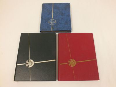 trois cahiers de couleurs différentes sont alignés sur une surface blanche