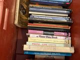 many books stacked in a red box on the floor