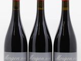 three bottles of red wine sitting on top of a white table