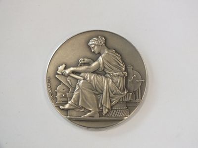une image représentant une médaille d'argent sur laquelle figure une femme assise sur une chaise