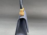 a small blue purse with a yellow button on the handle
