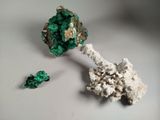 un petit morceau de minéral vert sur une surface blanche