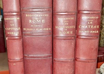 trois livres rouges sont empilés les uns sur les autres sur une étagère