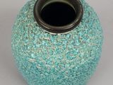 a blue vase with a black top on a white surface