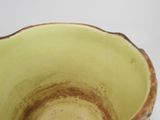 a close up of a green bowl on a white surface