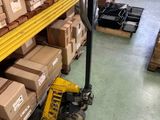 Les cartons sont empilés sur une palette dans un entrepôt à l'aide d'un diable.