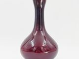 a red vase that is sitting on a white surface