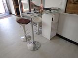 une table en verre avec deux tabourets devant