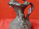 un vase en métal orné d'un oiseau, posé sur un tissu rouge