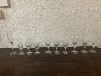plusieurs verres à vin vides alignés sur une table devant un mur