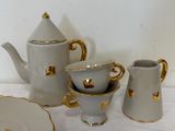 a white and gold tea set on a white table