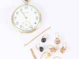 une photo représentant une montre de poche et d'autres bijoux posés sur une surface blanche