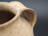 a clay vase with a handle on a table