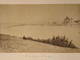 une photo en noir et blanc d'un homme assis sur une colline surplombant un plan d'eau