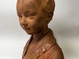 a clay bust of a young boy with a collared shirt