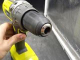 someone is holding a cordless drill in their hand near a piece of glass