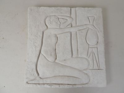 un relief blanc représentant un homme assis sur une table