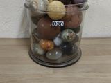 a glass jar filled with different colored rocks on a wooden table