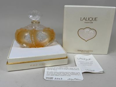 une photo d'un flacon de parfum dans une boîte, avec une étiquette