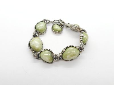 un gros plan d'un bracelet composé de perles vertes sur un fond blanc