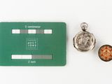 a green card with a picture of a man on it next to a silver pocket watch