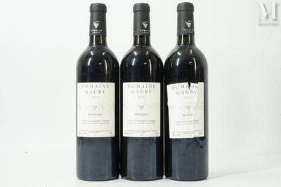trois bouteilles de vin sont alignées sur une surface blanche
