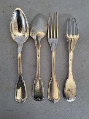 quatre cuillères en argent et une fourchette sont alignées sur une table