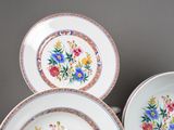 three plates with flowers painted on them on a table