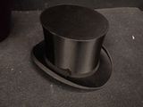 a black top hat sitting on the floor next to a trash can