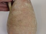 a hand that is holding a small vase on a table